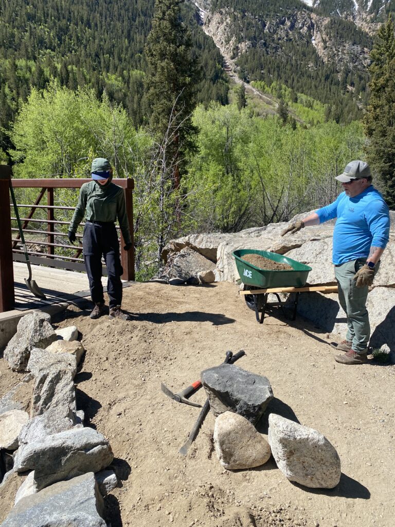 People hauling material in a whel barrel at a community Stewardship event