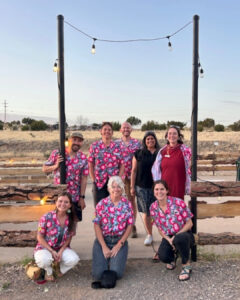 CDTC staff pose under hanging lights outside in their pink Hawaiian staff shirts.
