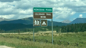 Green and brown highway signs for Kenosha Pass and Colorado Trail. 