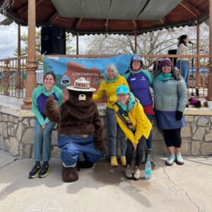 CDTC staff posing with Smokey the Bear in front of a gazebo with the Trail Days banner hanging behind.