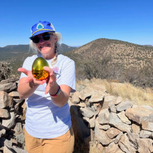 Jaime Jennings, a CDTC staff member, holds the golden egg she found with a desert landscape in the background.