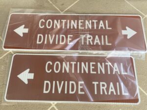 Continental Divide Trail brown signs set on a table wrapped in plastic.