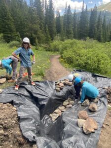 A group of trail volunteers digging a rock underdrain. 