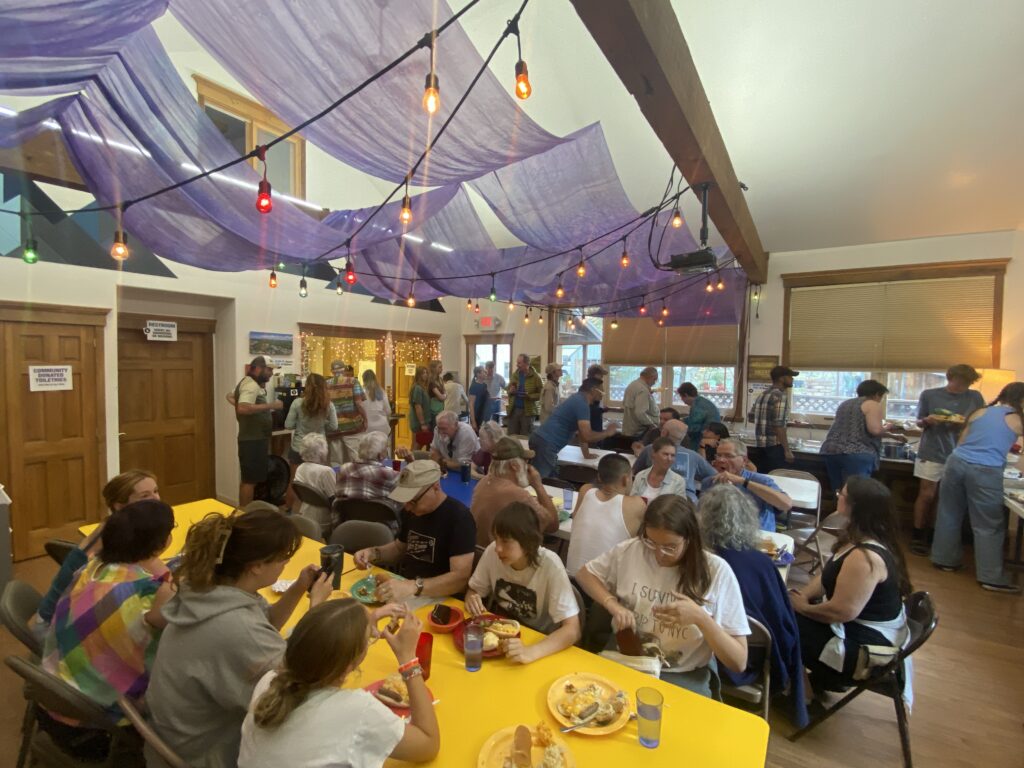 A large group of people sitting down having a potluck dinner